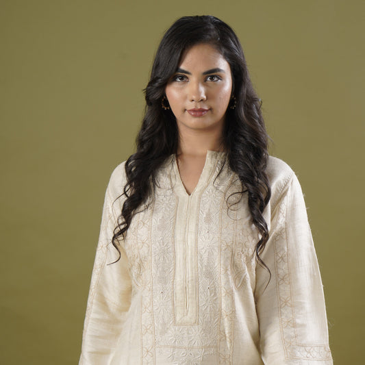 Woman wearing a light-colored dress against a plain background