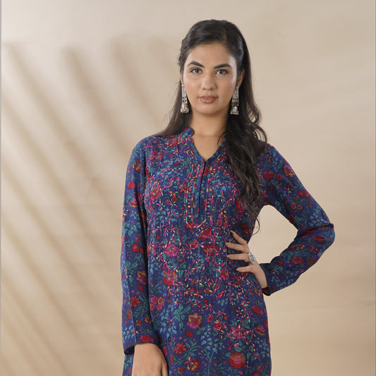 Woman wearing a blue floral dress standing in front of a white column.
